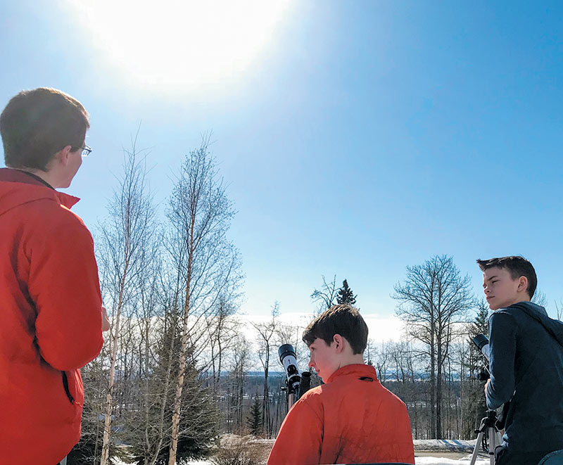 Two event participants listen intently as UAF physics student Jason Beedle explains solar physics.