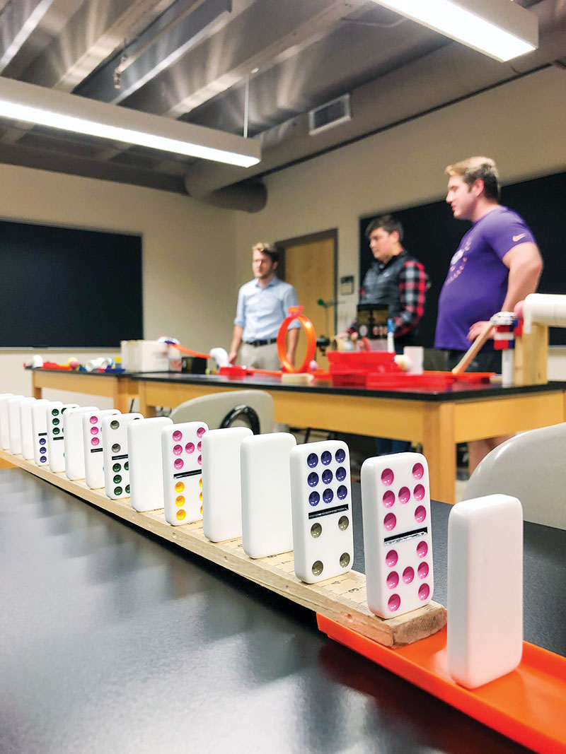  SPS students (L-R) Owen Johnson, Bryan Crow, and Kale Altman admire their work before setting off the Rube Goldberg machine. Photo by Abbigail Fahrenkamp.