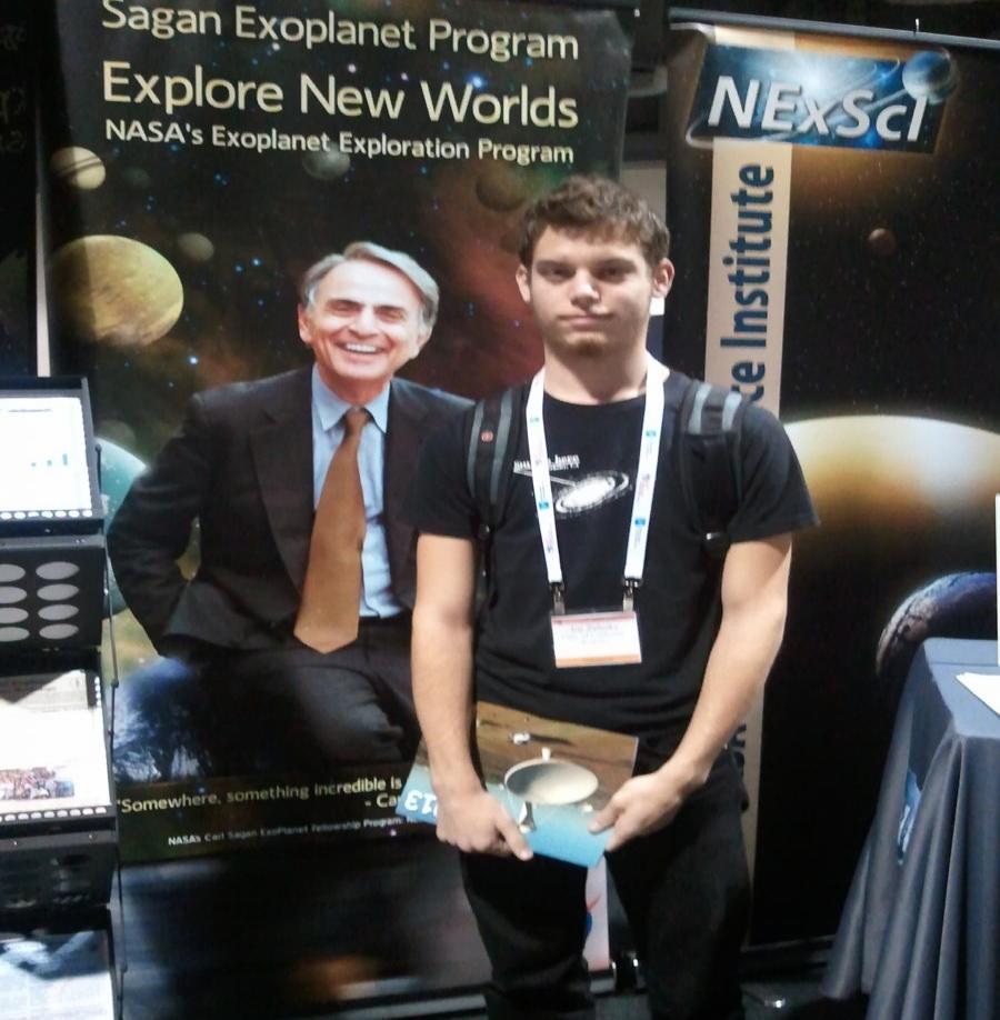 SPS Reporter Joe Zalesky stands by a poster of his long time hero, Carl Sagan at a booth in the conference hall. Photo Courtesy of Joe Zalesky.